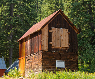 Rustic two-story wood-frame Jailhouse with the window on one end boarded up.