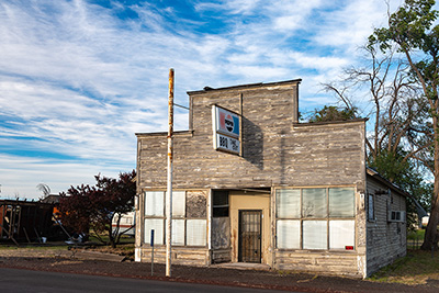 An old building with a Pepsi sign hanging over the front door.