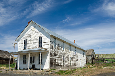 A 2-story building with 5 windows along the long side. The paint has almost all pealed off the building and it looks abandoned.