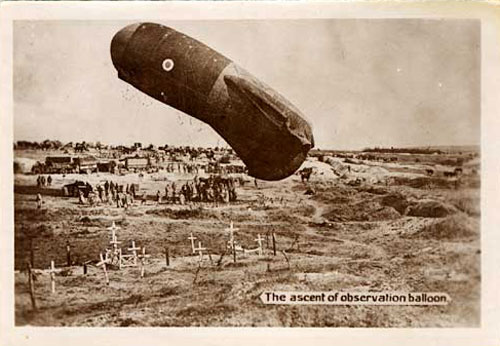 A hot air balloon pointed skyward begins to rise as a crowd of poeple watch. Rows of crosses as gravemarkers in foreground.