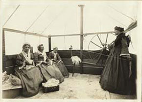 Women dressied in old fashioned dresses show how to spin wool during World war i