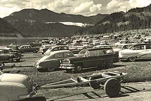 Dozens of cars lined up on the bank of Detroit lake. Some with boat trailers attached to the back.