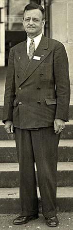 Full length photo of William Penn Lewis in suit and tie standing in front of steps.