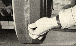 A man's hand with his finger digging into part of a used tire.