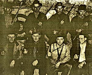 8 men in hats holding long guns smile for the camera.