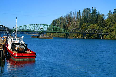 Arched bridge over calm river. A fishing boat tied to a dock.