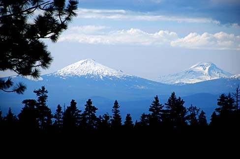 Two snowy mountain peeks in a forested landscape