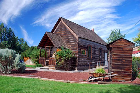 Rustic log cabin with an outhouse nearby.