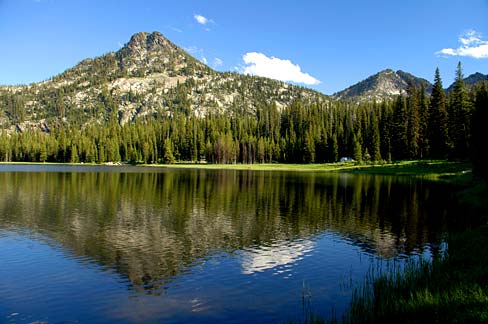 boat docked on the edge of lake with mountain in the background