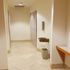 A hallway with lockers on either wall and a drinking fountain.