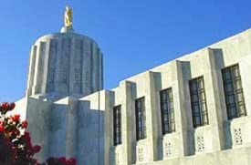 The Capitol Building in Salem shown looking up at the gold man statue (pioneer) with blue sky in background.