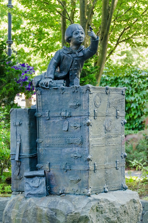 Outdoor sculpture of a child reaching out a hand on which a butterfly has landed.