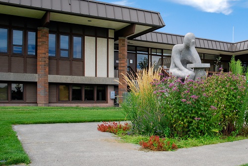 sculpture of student sitting at desk in front of building