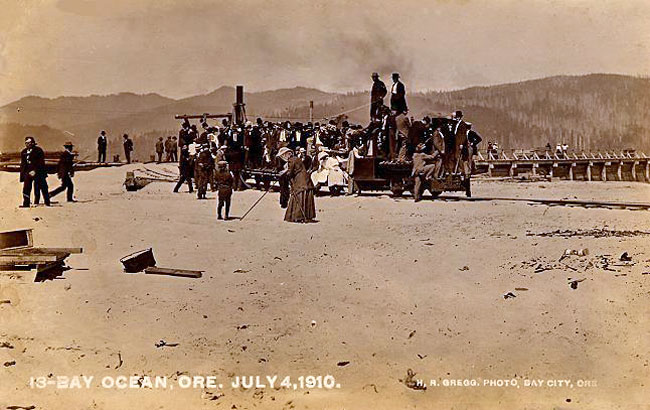 Photo of people standing on a beach next to a rail line in 1910.