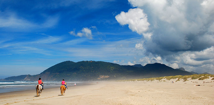 riding horses on the beach with hills in the distance