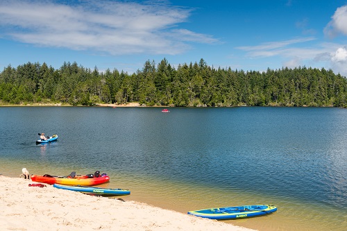 Cleawox Lake with a few kayaks on the shore and 1 person in a kayak on the lake.