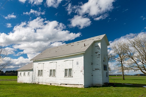 A long single story building with 3 tall windows on one half and shorter roof with smaller 3 windows on the other half.