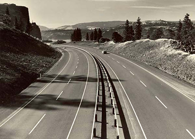 A 4 lane highway, 2 lanes going each direction, with a single car in one lane.