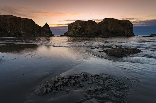 Large rock formations along the beach at sunset.