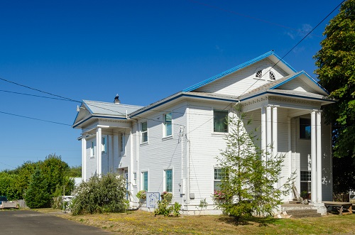 3 story building with grand pillars in the front that reach from the groud to the roof provides cover over the entry way.