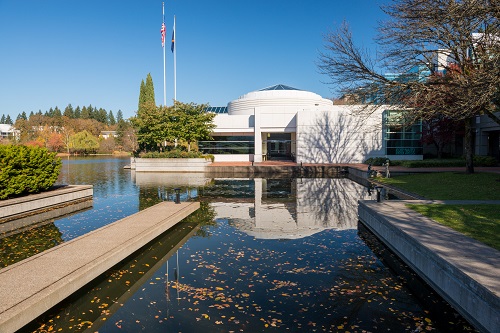 Modern looking building with a man made water pond in front. 