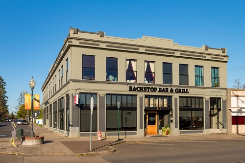 2 stoy building takes up corner of city block. On front is printed "Backstop Bar & Grill"