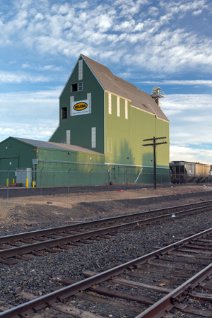 A grain elevator next to double train tracks.