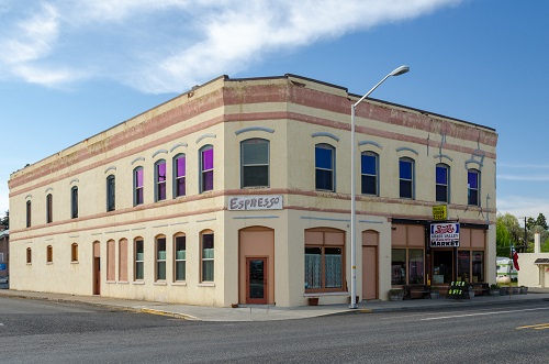 Two-story commercial building that takes up a block. A sign for espresso on the corner door of the building.