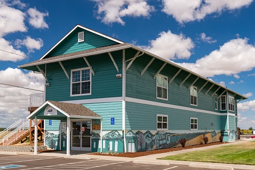 Rectangular, wood frame building. Gable roof with brackets. Shiplap siding. 