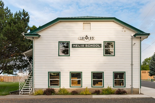 2-story Helix school building with the date 1889 and a freemasonry symbol painted on the side above the school name.