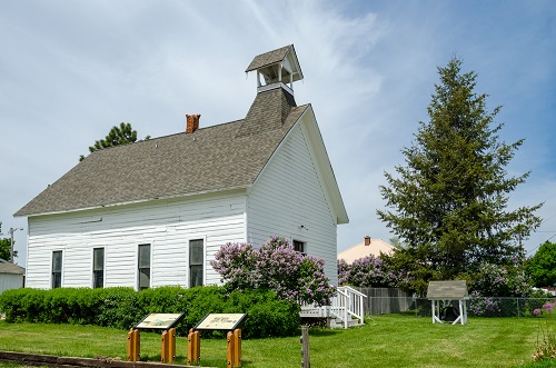 A small church, which could be just 1 room. It has a bell tower & chimney on the roof. 4 tall rectangle windows on side. 