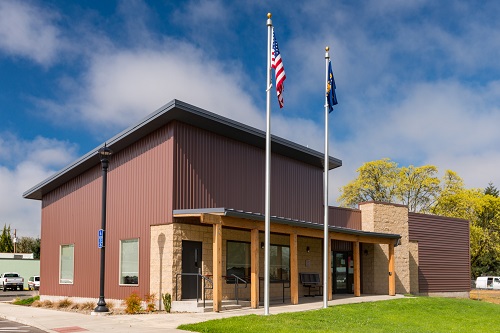 Square building with top side of square at an angle so the roof slant and water runs off. 2 flags fly on flag poles.