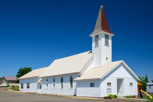 Long, 1-story church split architecturally in 3 by having 3 different roof heights. A bell tower between 1st & 2nd sections.