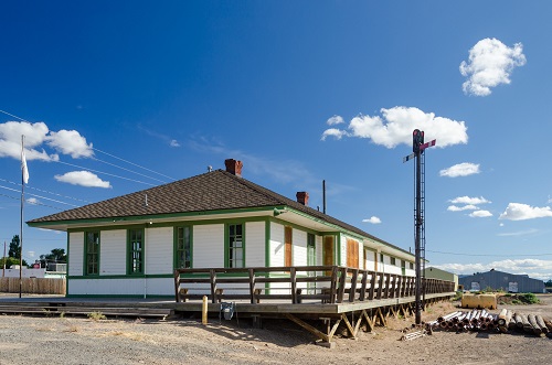 Single story train station with wrap around deck lining one side. The Deck is raised from the group a couple feet.