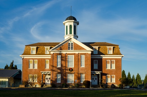 3-story brick building with tower in center set back from main street. Stone foundation. Originally 1867 college