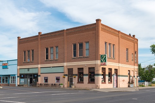 2-story square brink building on the corner of a city street. A sign for Sprite and Coke hangs from the corner.