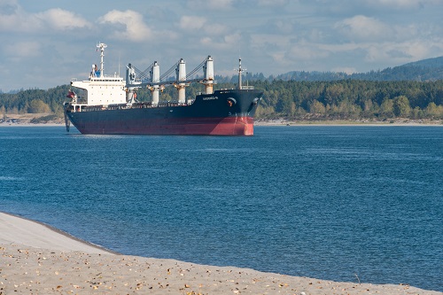 Container ship with 4 cranes on deck for handling containers floats on the river. 