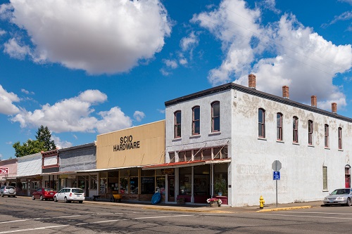 Street view of commercial business buildings in downtown Scio. One building says "Scio Hardware" on the side.