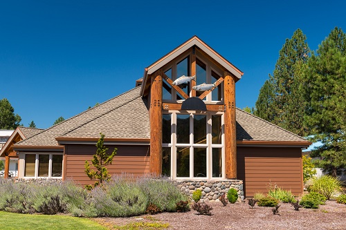 Single story library built of heavy timber & log construction. Tall front window has art work of swimming salmon sculpture.