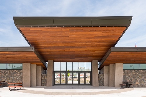 Modern combination building with stone walls & wood roof. Roof has sections at different heights & lengths jutting out.