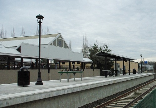 A clean, raised cement platform about 2 feet from train tracks. Part of the platform has a covered area for rainy days.