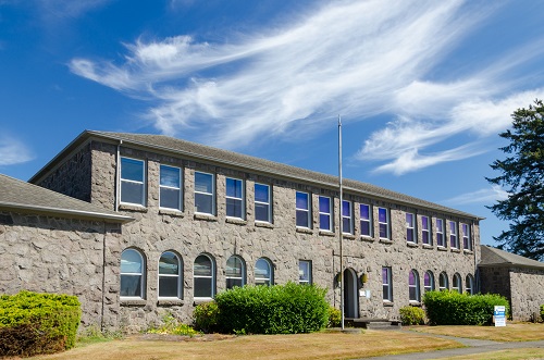 2-story stone building. 15 rectangle windows on the 2nd floor. 1st floor has windows with arched tops.