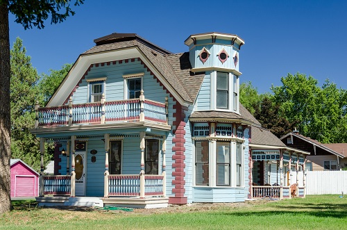 Simple cottage with ornate Renaissance Rivival style octagonal tower. Spindles, rosettes & pie crust moldings typical of style.