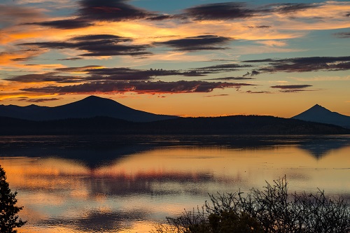 reflection of orange sunset on lake and dark mountains in the background