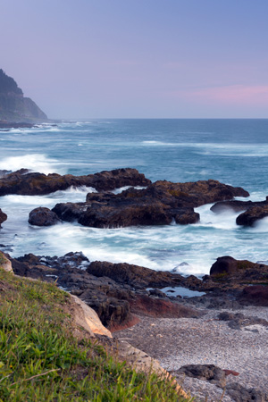 A rocky coast line at dusk with white capped waves.