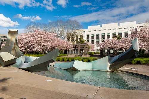 3 story office building about the length of a city block. Cherry trees blossom in front.